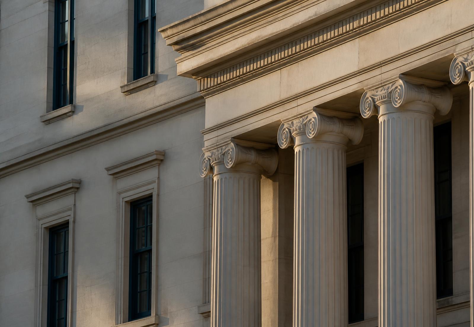 Detalle de fachada institucional de piedra con columnas clásicas